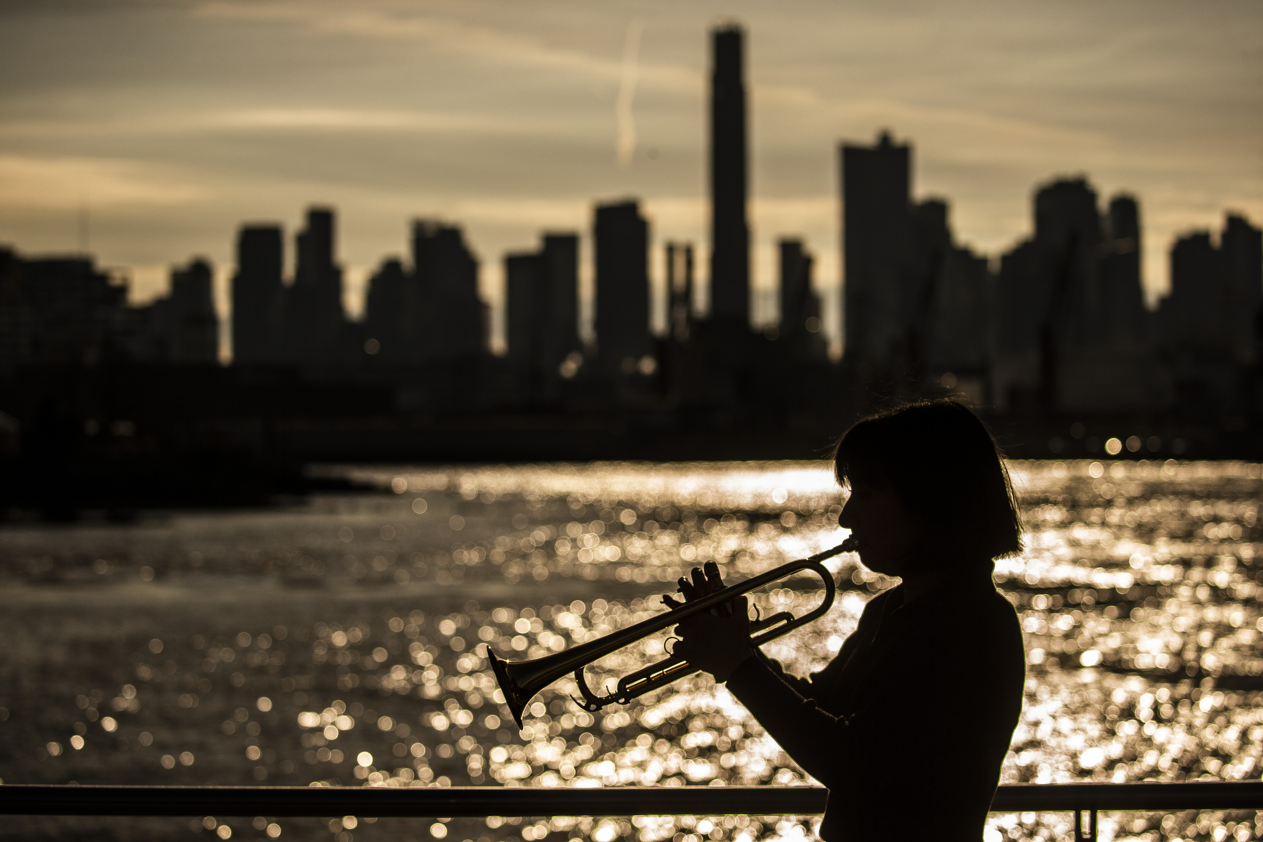 Silhouette of honoree Bell Thompson playing her trumpet in front of the New York City skyline