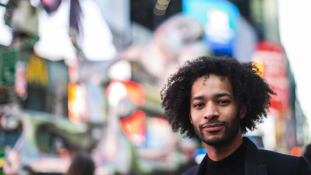Honoree Jordan Dobson standing on an NYC street with bright lights behind him