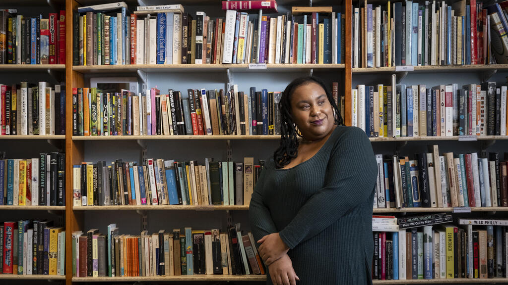 Honoree Sabriaya Shipley wearing a green dress and leaning on a bookshelf