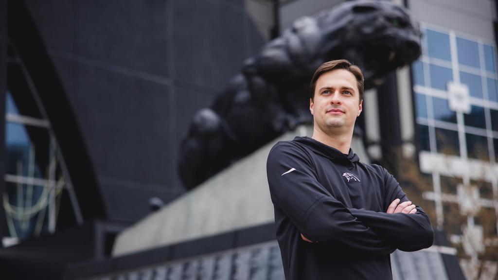 Joseph Glennon Jr. poses in front of the Carolina Panthers' statue.