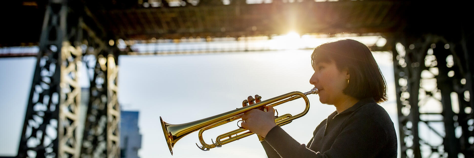 Honoree Bell Thompson playing her trumpet in front of a New York City bridge