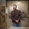 Daniel Clark smiles in front of his woodshop. 