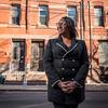 Simone Snead standing outside neighborhood buildings. 