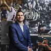 Zach Gelb standing front of a mural of photos featuring great sports moments in history