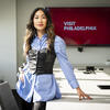 Honoree Nguyen leaning on a conference table in front of a screen that reads Visit Philadelphia