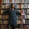 Honoree Sabriaya Shipley wearing a green dress and leaning against a bookshelf