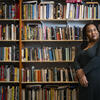 Honoree Sabriaya Shipley wearing a green dress and leaning on a bookshelf