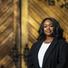 Honoree Carine Wellington smiling and standing in front of a gold door