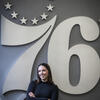 Morgan Pivovarnik stands in front of the Philadelphia 76ers logo.