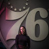 Morgan Pivovarnik stands in front of the Philadelphia 76ers logo.
