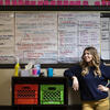 30 Under 30 honoree Michelle Ferguson Shore leaning against storage boxes in front of a dry erase board featuring lesson plans and a calendar