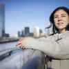 30 Under 30 honoree Andrea Behler leaning on a bridge railing and looking up. Her hands are clasped and she's wearing a winter coat.